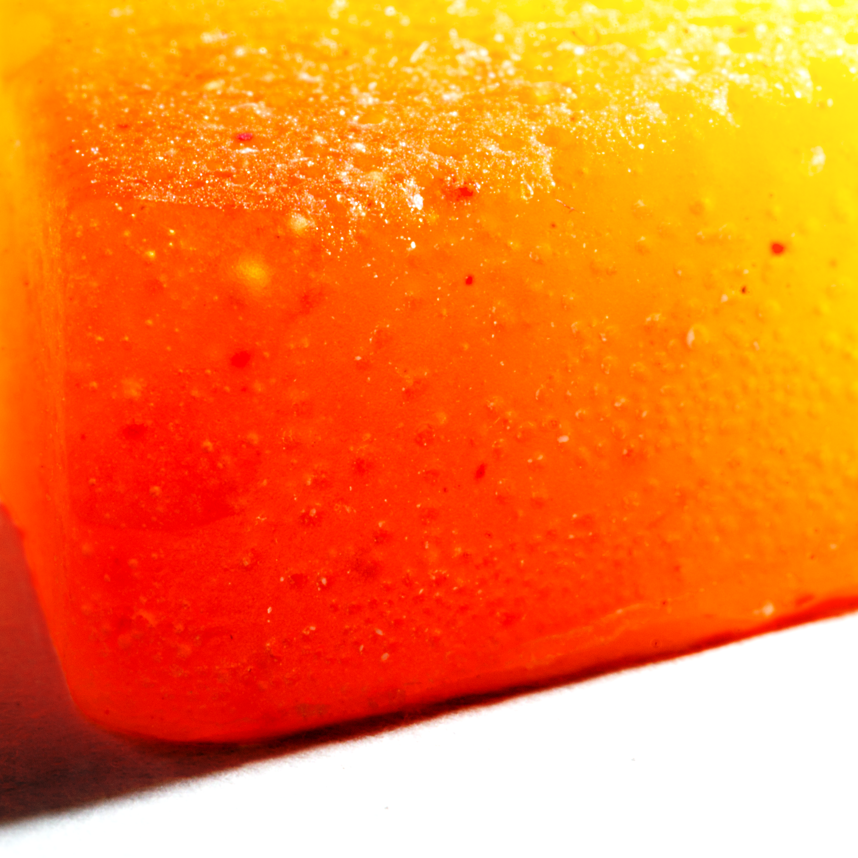 Close-up of a bright orange and yellow gummy candy on a white background